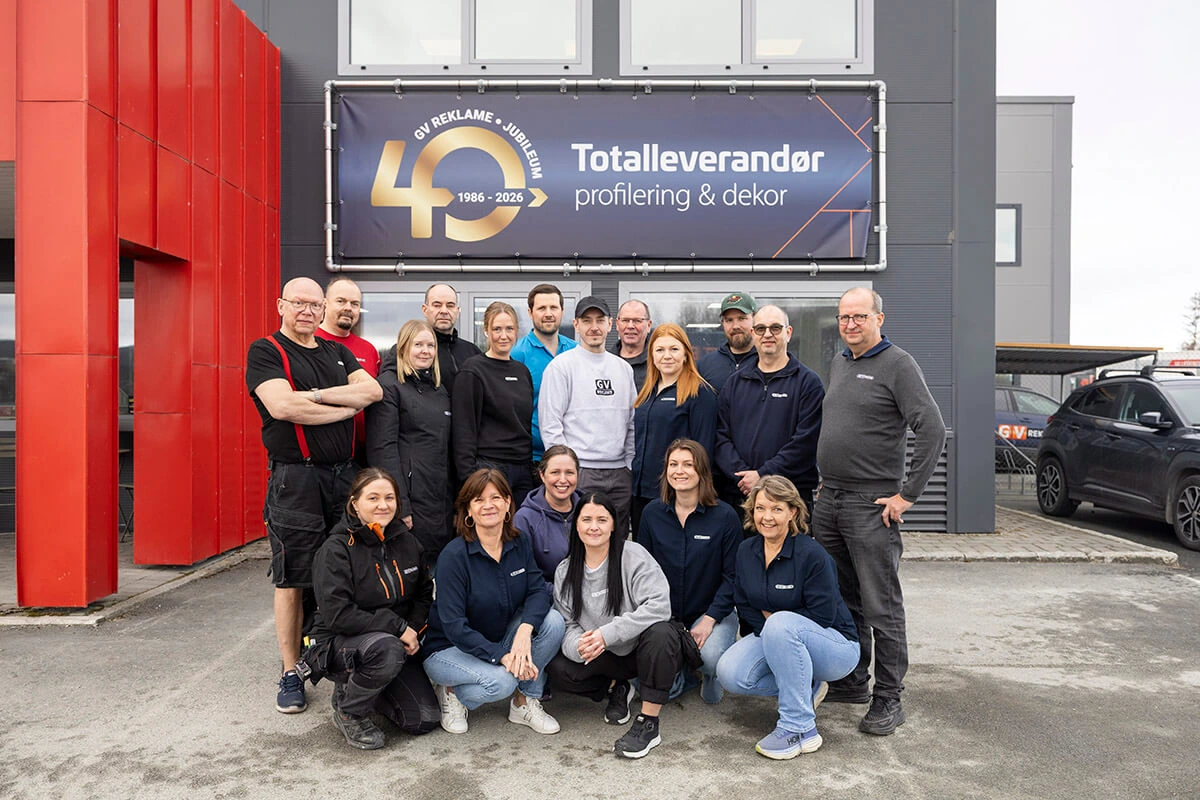 Gjengen på GV Reklame utenfor lokalet med stort 40-årsjubileumsbanner bak.